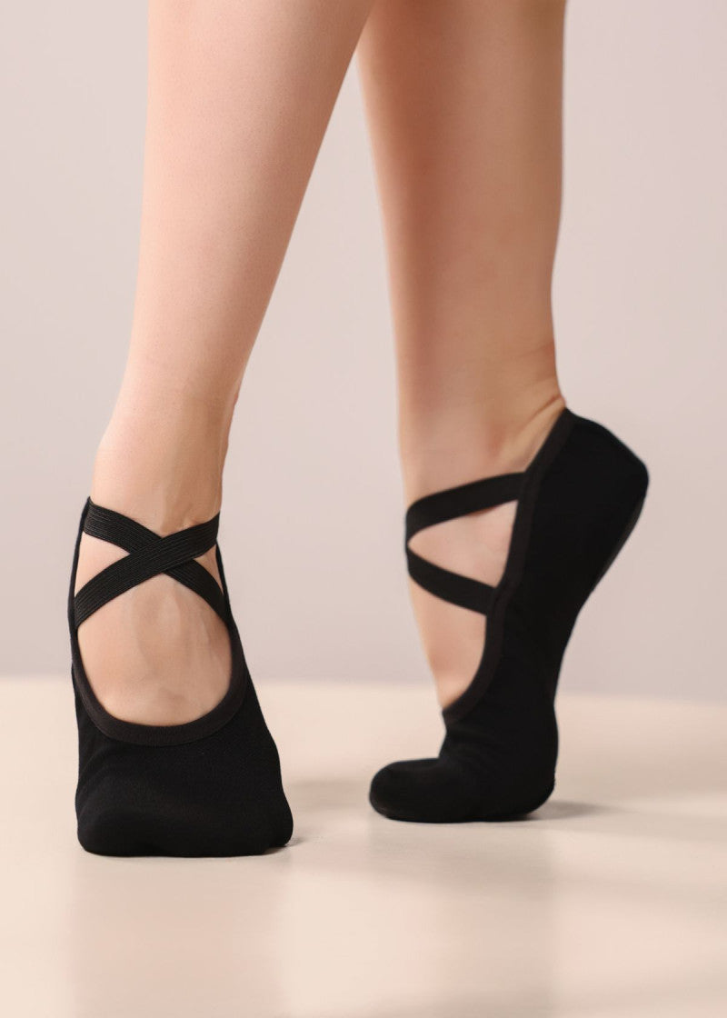 Black ballet slippers with crisscross ankle straps worn on a dancer's feet- RELEVE Stretch Ballet & Dance Shoes – Side View