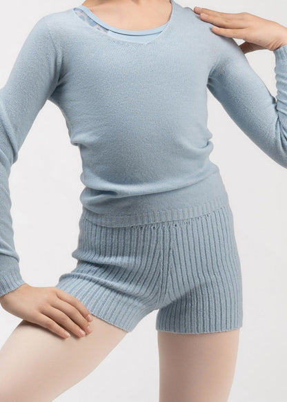 A child wearing a light blue ribbed knit long-sleeve top and matching ribbed knit shorts 